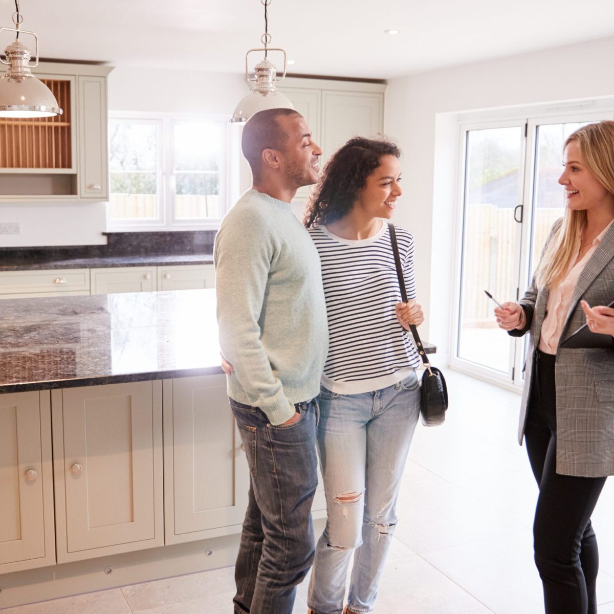 Female Realtor Showing Couple Interested In Buying Around House Female Realtor Showing Couple Interested In Buying Around House
